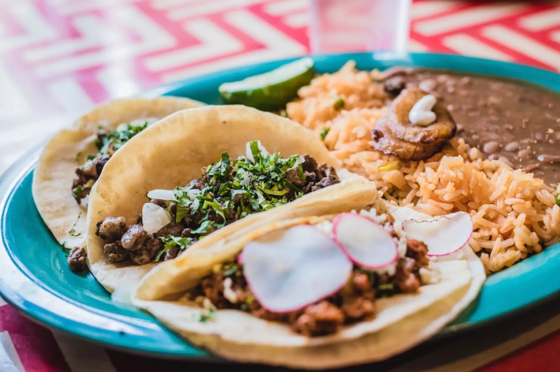 Mexican tacos, rice, and beans on a plate.