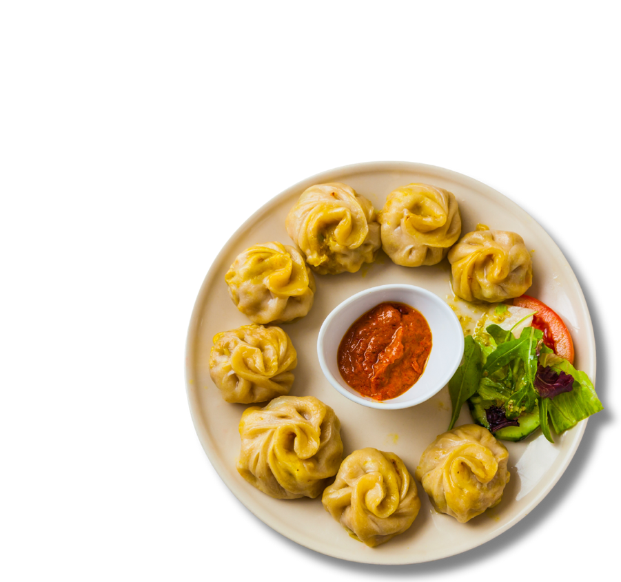 A plate of dumplings in a circular plate with dipping sauce in the middle.