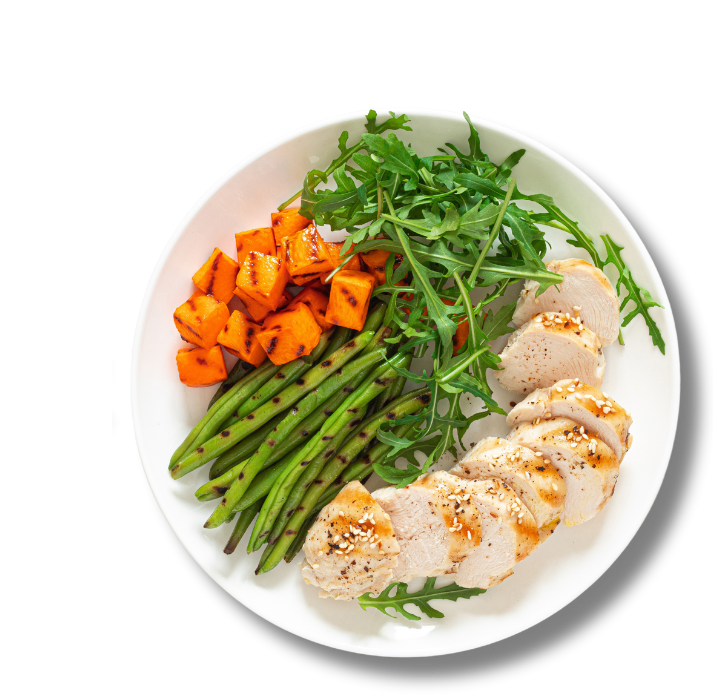 A plate with green beens, arugula salad, sweet potatoes and chicken breast.