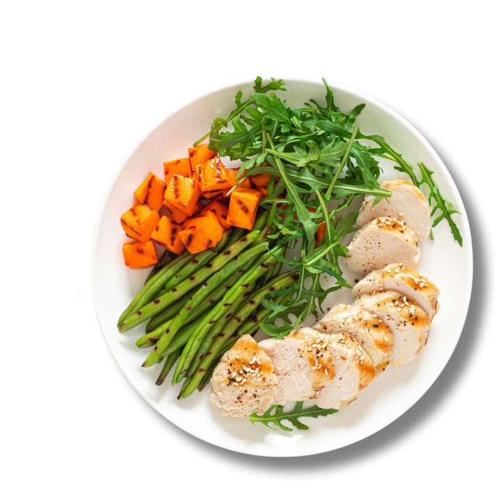 A plate with green beens, arugula salad, sweet potatoes and chicken breast.